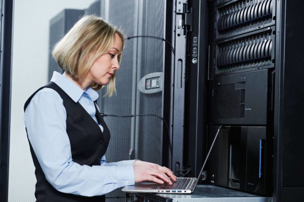 female engineer works with laptop in data center